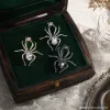 Three vintage crystal spider brooches, silver, gold and black alloy pins, Muslim-style white display stand undefined